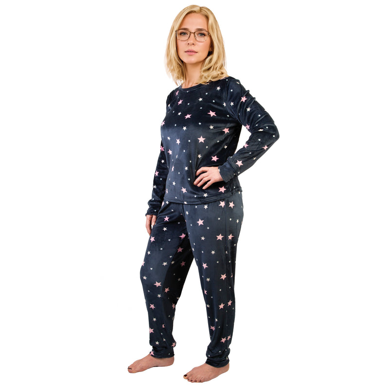Woman wearing a navy blue pajama set with pink stars on a white background