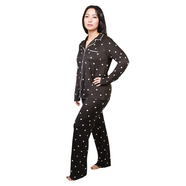 Woman wearing a black pajama set with white polka dots on a white background
